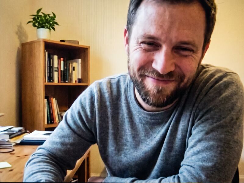 The visitor on his webcam, at his desk at home